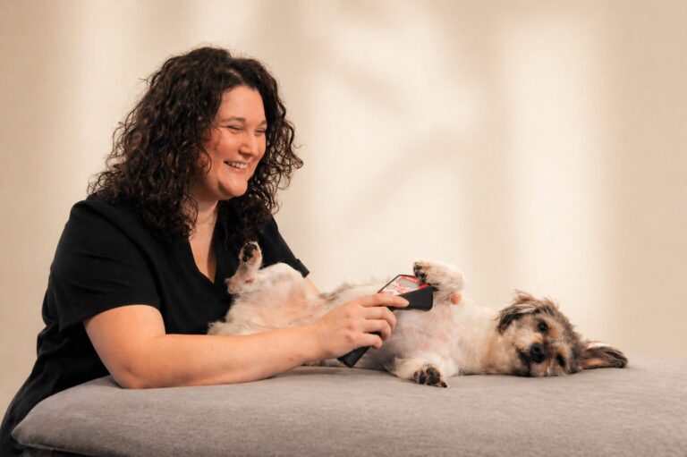 Therapeutin sitzt ruhig neben einem kleinen Hund und arbeitet sanft am Hundekörper